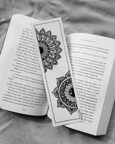 an open book with black and white designs on the cover is laying on a bed