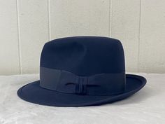 Vintage 1940s or 1950s Royal Stetson fedora hat. Made of black felt (almost looks navy blue in the right light). Black grosgrain hatband. Has a felted and triple stitched brim. Lined in satin. Brown leather sweatband. ROYAL STETSON made by JOHN B. STETSON COMPANY. Sold at J. L. Hudson's Company, Detroit.  Size 7 1/2.  2 1/4" brim. Opening measures 6 3/4" X 8 1/4".  In excellent condition. Vintage Fedora For Kentucky Derby With Flat Bill, Vintage Navy Hat With Flat Brim, Classic Navy Hat With Flat Brim, Retro Formal Fedora With Wide Brim, Retro Fedora Hat For Formal Occasions, Classic Navy Wide Brim Hat, Retro Wide Brim Fedora For Formal Occasions, Navy Fitted Hat With Short Brim, Classic Navy Flat Brim Hat