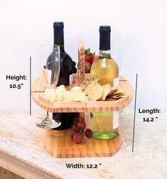 a wine bottle and two glasses sitting on a wooden tray with cheese, crackers and strawberries