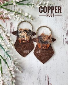 two keychains with fur on them sitting next to flowers