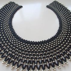 a black and silver beaded necklace on a white surface