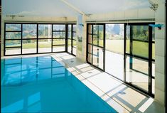 an indoor swimming pool with glass doors and windows