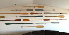 a living room filled with furniture and lots of different types of paddles on the wall