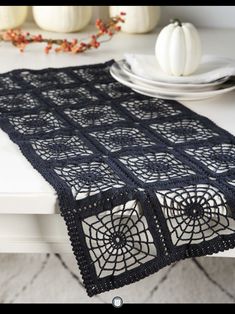 the table runner is made from crochet and sits on top of a dining room table