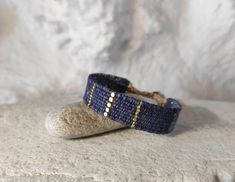 two bracelets sitting on top of a rock next to a stone wall and white rocks