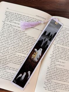 a bookmark with two ghostes on it and an open book in the background