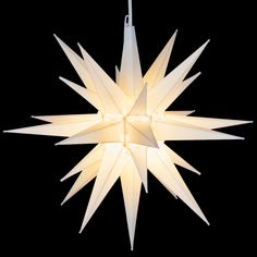 a white star shaped light hanging from a string on a black background in the shape of a christmas tree ornament