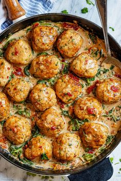 a skillet filled with meatballs covered in gravy and garnished with herbs