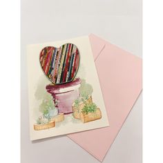 a card with a potted plant and heart on the top, next to a pink envelope