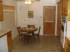 a kitchen with a table and chairs in the middle of it, next to an open door