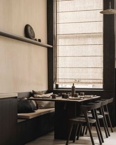 a table with four stools in front of it and a window covered by blinds