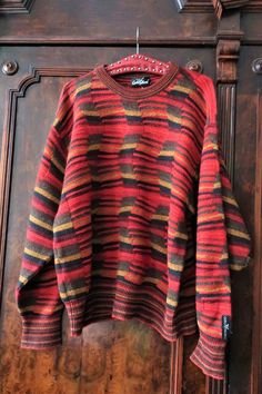 Beautiful True Vintage Carlo Colucci knit sweater from the 1990s. Made from a high quality wool blend fabric with multi color, structured wave knit in a warm color palette. Crew neck, relaxed cut, wide sleeves. Striped neck, cuffs and waistband. Carlo Colucci brand patch above the left cuff. Unisex. BRAND: Carlo Colucci ERA: 1990s COLOR: Red, sand, mustard, brown, khaki FABRIC: 70% new wool, 30% acrylic SIZE: Vintage men's size 52, fits best men's size L, but can also be worn by women - please c Retro Striped Knitted Sweater, Striped Wool Sweater With Long Sleeves, Striped Wool Sweater With Crew Neck, Striped Wool Crew Neck Sweater, Winter Jacquard Knit Striped Sweater, Winter Striped Jacquard Knit Sweater, Striped Jacquard Knit Sweater For Winter, Striped Knit Sweater For Fall, 90s Brown Long Sleeve Sweater