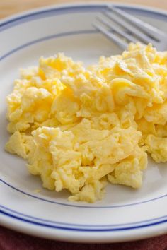 scrambled eggs on a plate with fork and knife next to it that says fluffy scrambled eggs