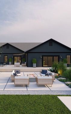 an outdoor living area with couches and tables in front of a large black house