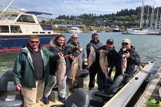 a group of men standing on top of a boat holding fish