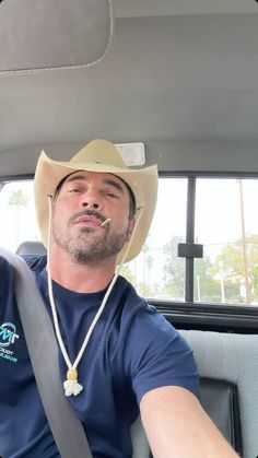 a man wearing a cowboy hat sitting in the back seat of a car