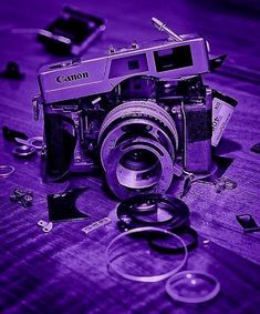 an old camera sitting on top of a wooden table next to other broken up objects