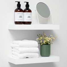 two white shelves with towels, soaps and a mirror on top of each shelf