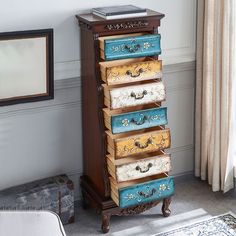 an old dresser with five drawers painted in blue and yellow, next to a window