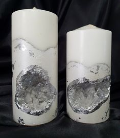 two white candles with silver foil on them