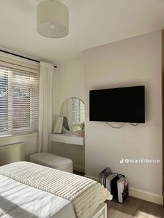 a bedroom with a bed, mirror and television mounted on the wall in front of it