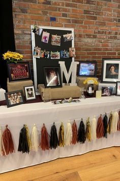 a long table with pictures and tassels on it in front of a brick wall