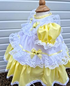 a yellow and white dress with lace on the bottom is sitting in front of a garage door