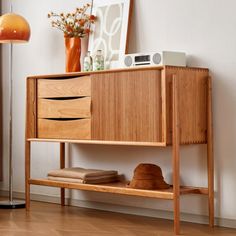 a wooden cabinet sitting on top of a hard wood floor next to a lamp and window