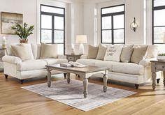 a living room with two couches, a coffee table and lamps on the floor