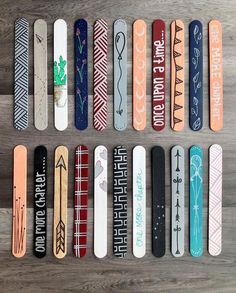 many different colored skateboards are lined up on the floor with words painted on them