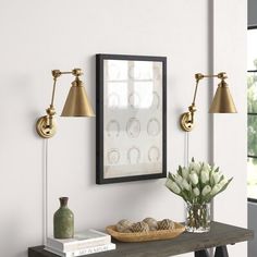 a table with two lamps and a vase on it next to a mirror, books and flowers