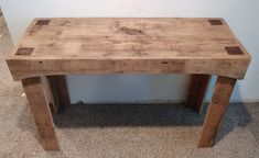 a wooden table sitting on top of a carpeted floor next to a white wall