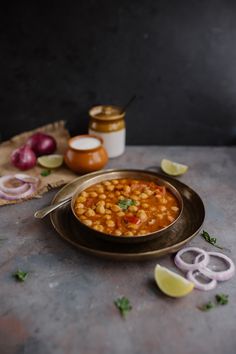 a bowl filled with beans and onions on top of a table next to onion slices