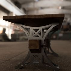 a wooden bench sitting on top of a cement floor next to a metal frame structure