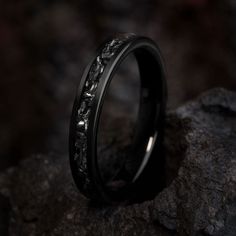 a black wedding ring sitting on top of a rock