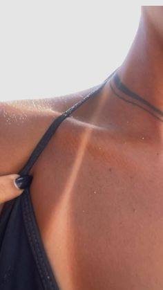 a close up of a woman's neck wearing a necklace with an arrow on it