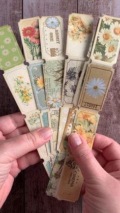 a person holding up some old bookmarks with flowers on them and the words written in different languages