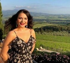 a woman standing on top of a balcony next to a lush green field