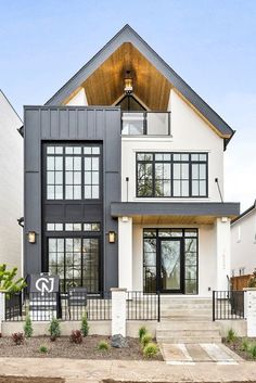 a large white and black house with lots of windows on the top floor, stairs leading up to the front door