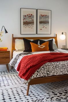 a bedroom with two framed pictures above the bed, and a black and white patterned rug on the floor