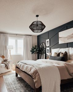 a bedroom with a large bed and white curtains on the window sill, next to a chair