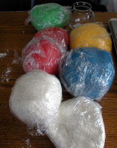 several balls of yarn are wrapped in plastic and sitting on a table next to a laptop