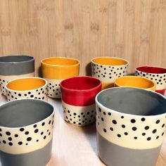 many different colored bowls sitting on top of a wooden table with polka dot designs in them