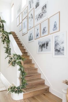 the stairs in this house are decorated with pictures and garlands on them, as well as greenery