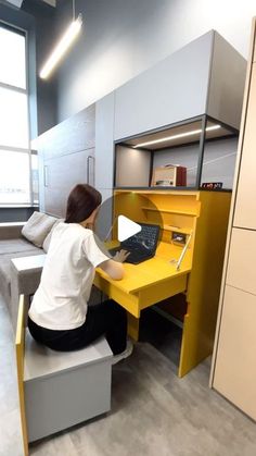 a woman sitting at a yellow desk with a laptop computer on top of her lap