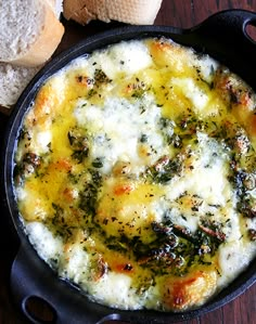 an iron skillet filled with cheese and broccoli on top of a wooden table