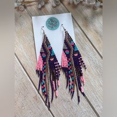 a pair of pink and blue beaded earrings sitting on top of a piece of paper