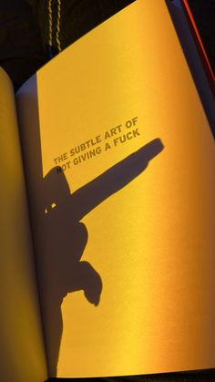 an open book with the shadow of a person holding a skateboard in front of it