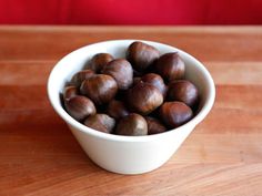 a white bowl filled with nuts on top of a wooden table