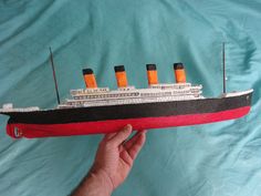 a hand is holding up a model of a ship